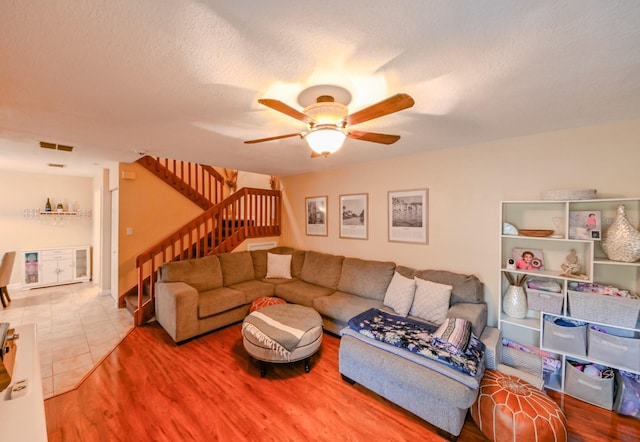 living room with ceiling fan, tile patterned flooring, and a textured ceiling