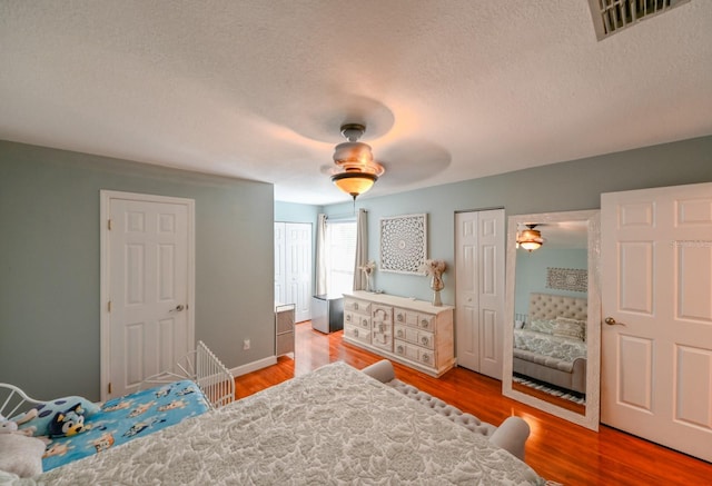 bedroom with a textured ceiling, hardwood / wood-style flooring, and ceiling fan