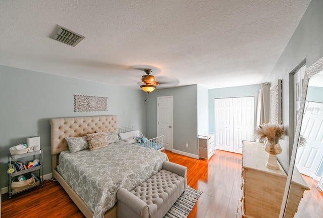 bedroom with hardwood / wood-style floors, ceiling fan, a textured ceiling, and a closet