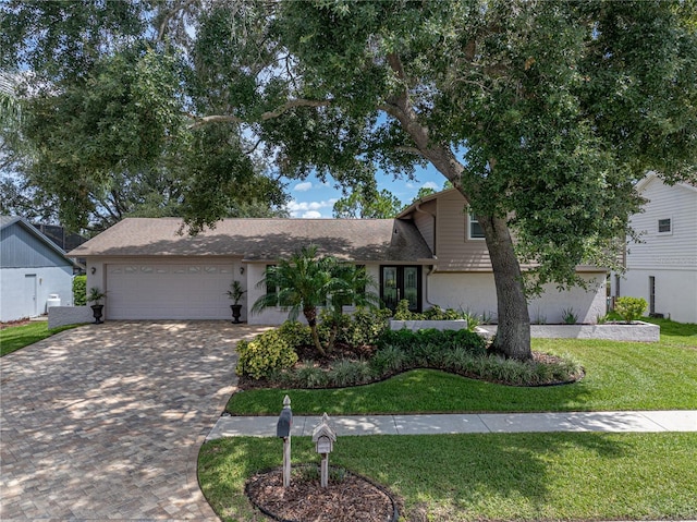 view of front of property featuring a garage, stucco siding, decorative driveway, and a front yard