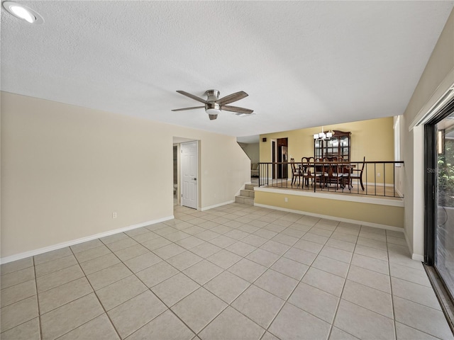 empty room featuring a textured ceiling, ceiling fan with notable chandelier, and light tile patterned flooring