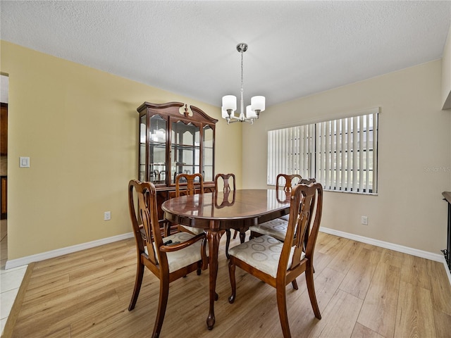 dining room featuring light wood-type flooring, a textured ceiling, and a notable chandelier