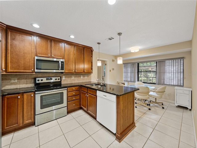 kitchen with pendant lighting, kitchen peninsula, appliances with stainless steel finishes, and tasteful backsplash