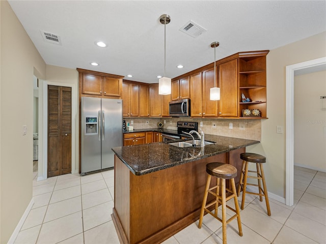 kitchen with hanging light fixtures, backsplash, stainless steel appliances, sink, and dark stone counters