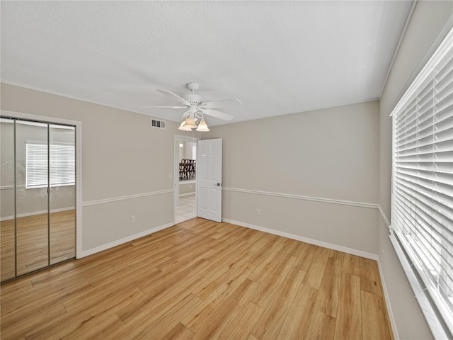 unfurnished bedroom featuring ceiling fan, a closet, and light wood-type flooring