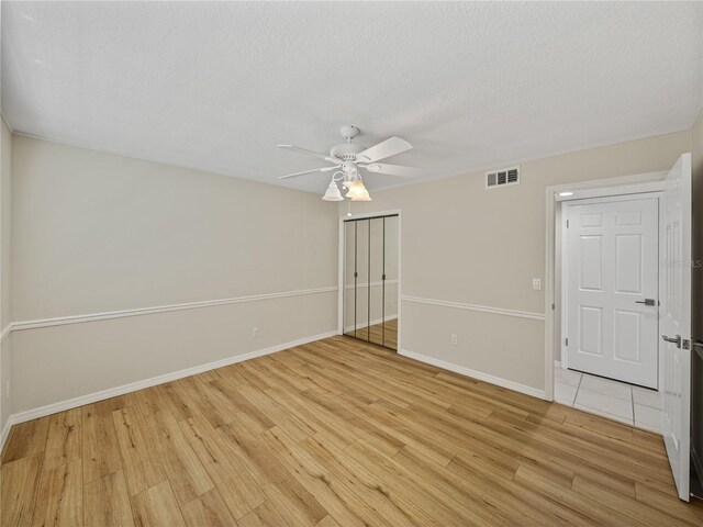 spare room with a textured ceiling, light hardwood / wood-style flooring, and ceiling fan