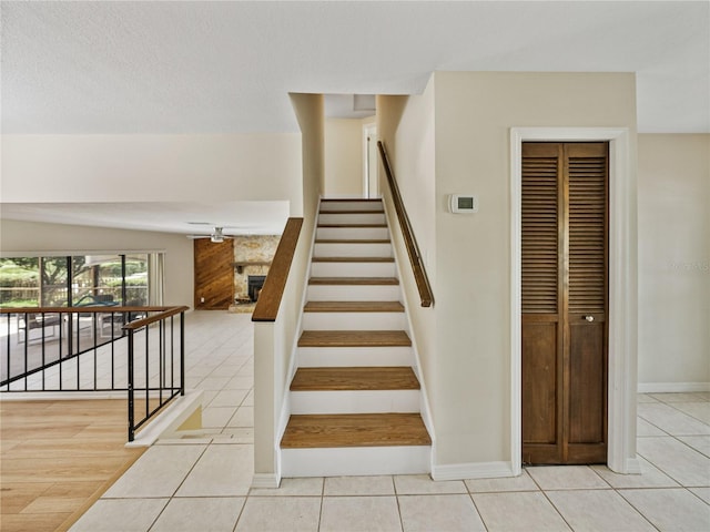 stairway with vaulted ceiling, tile patterned floors, and a large fireplace