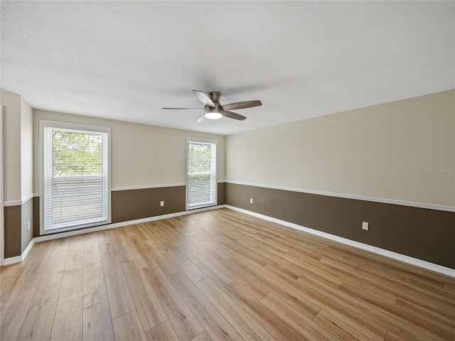 empty room featuring a wealth of natural light, ceiling fan, and light hardwood / wood-style floors