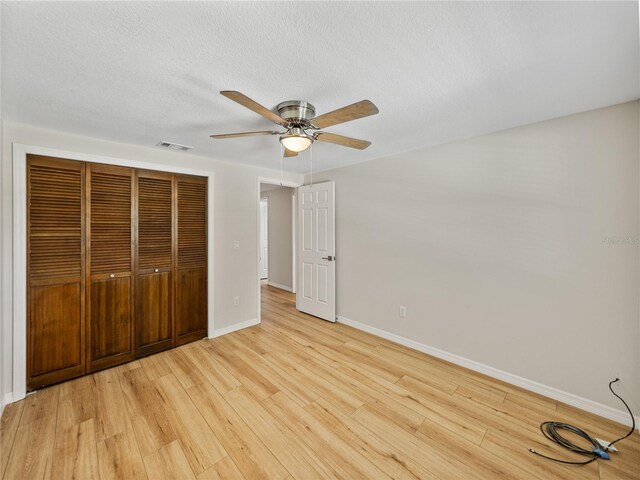 unfurnished bedroom with light wood-type flooring, a closet, ceiling fan, and a textured ceiling