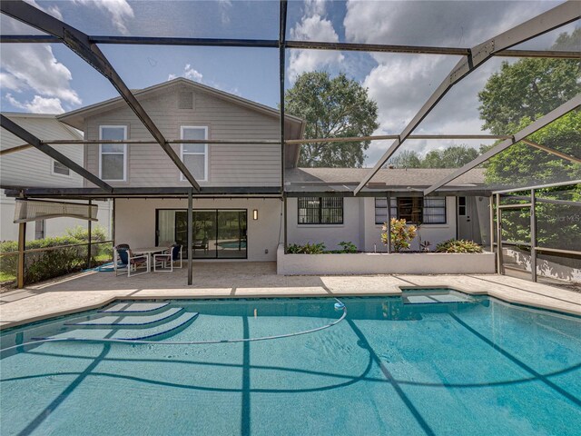 view of pool with glass enclosure and a patio