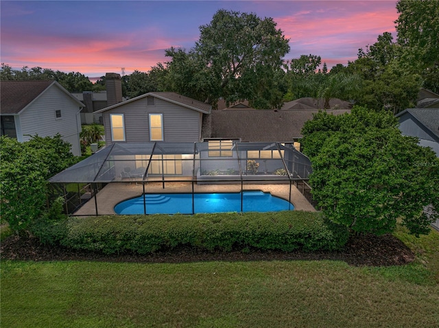 pool at dusk with a yard and a lanai