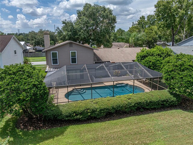 view of pool with a yard and glass enclosure