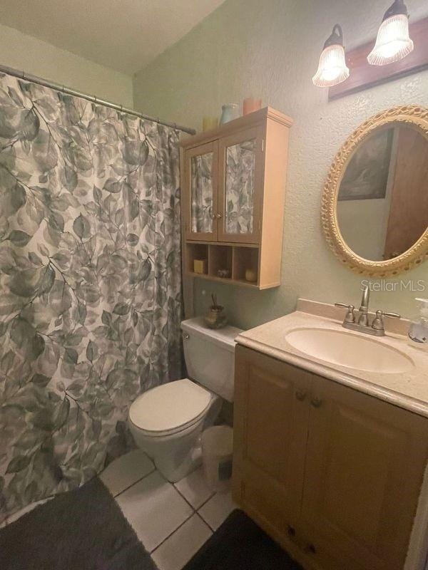 bathroom with vanity, toilet, a shower with curtain, and tile patterned floors