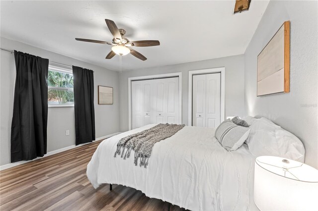 bedroom featuring dark hardwood / wood-style flooring, multiple closets, and ceiling fan