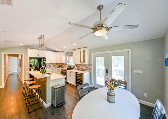 dining room featuring ceiling fan, dark hardwood / wood-style flooring, wine cooler, and vaulted ceiling