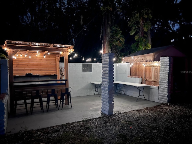 patio at twilight featuring a pergola and an outdoor bar