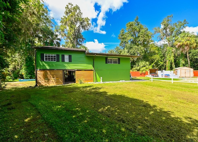 rear view of house featuring a lawn and a storage unit