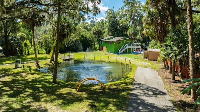 view of property's community with a yard, a storage unit, and a water view