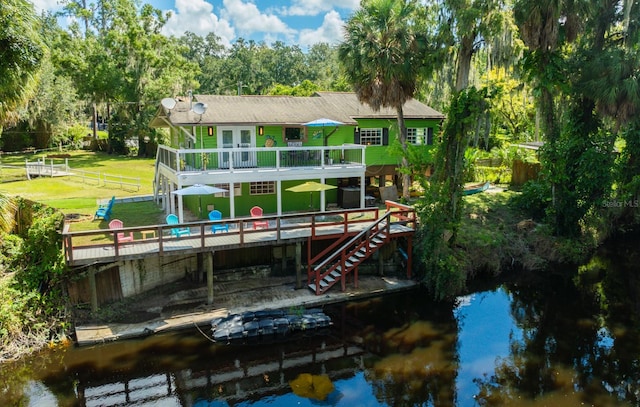 back of property with a lawn and a deck with water view