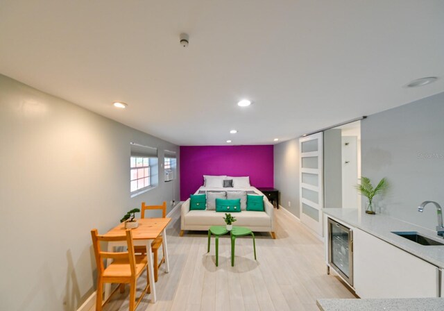 bedroom featuring beverage cooler, wet bar, and light hardwood / wood-style flooring