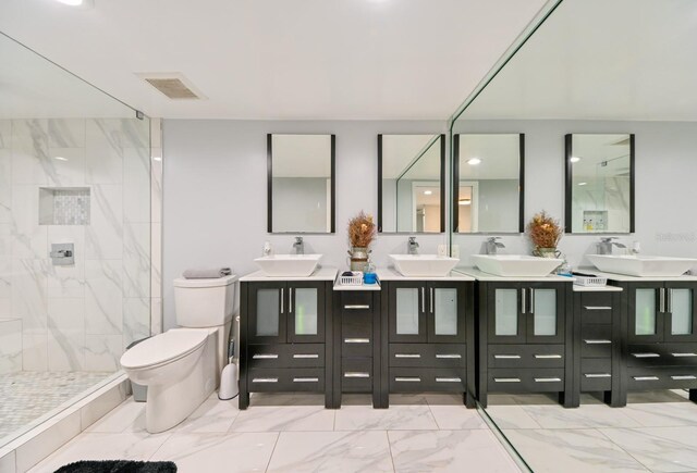 bathroom with vanity, toilet, and a tile shower