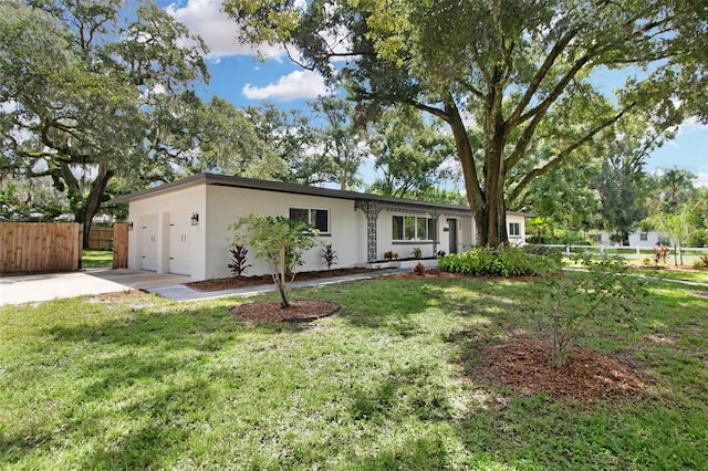 ranch-style home with driveway, a front yard, fence, and stucco siding