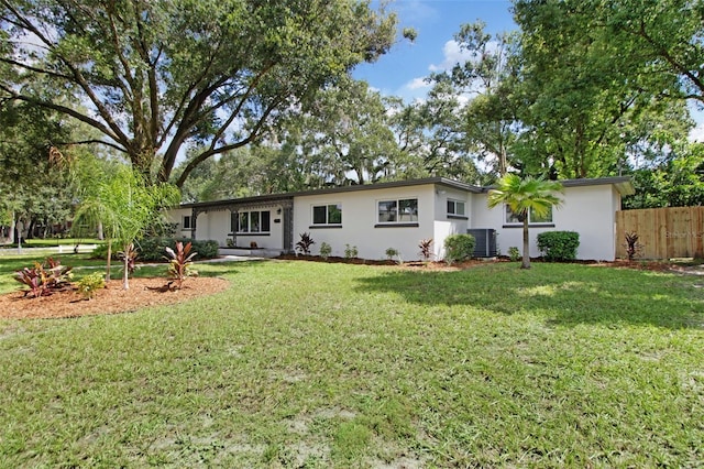 view of front of property with a front lawn, cooling unit, fence, and stucco siding