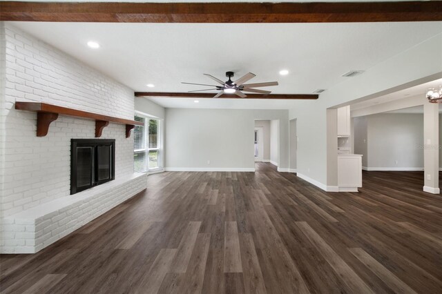 unfurnished living room featuring dark wood-type flooring, a brick fireplace, brick wall, and ceiling fan