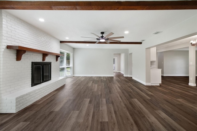 unfurnished living room featuring a brick fireplace, dark wood finished floors, visible vents, and baseboards