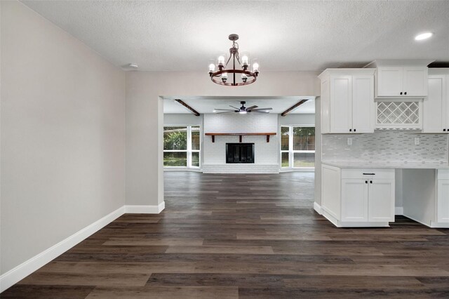 kitchen with a fireplace, ceiling fan with notable chandelier, white cabinetry, a textured ceiling, and dark hardwood / wood-style floors