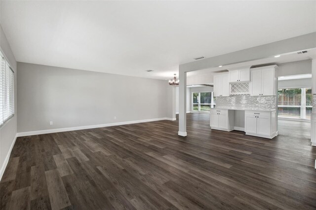 unfurnished living room featuring dark wood-type flooring and a notable chandelier