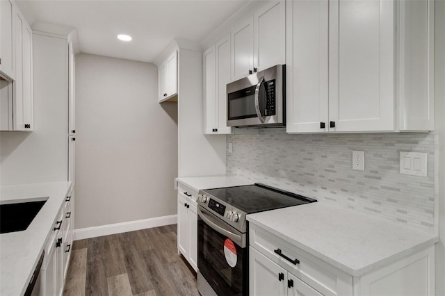 kitchen with light stone counters, dark wood finished floors, appliances with stainless steel finishes, white cabinets, and baseboards