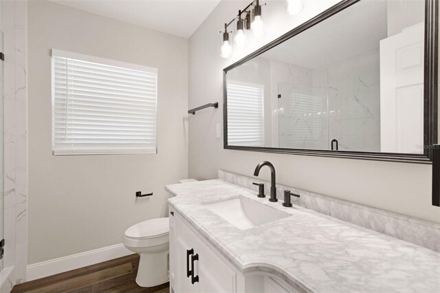 bathroom featuring a marble finish shower, baseboards, toilet, wood finished floors, and vanity