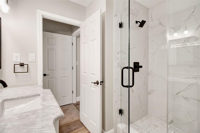 bathroom with hardwood / wood-style floors, walk in shower, and vanity