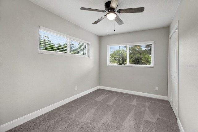 empty room with plenty of natural light, ceiling fan, and carpet flooring