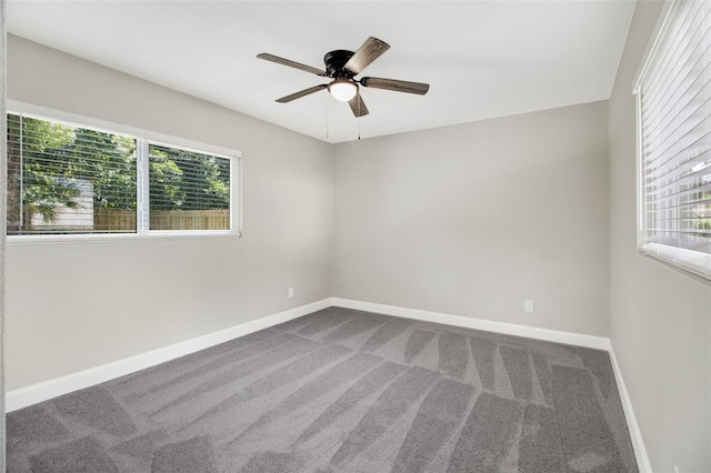 carpeted spare room with a healthy amount of sunlight, ceiling fan, and baseboards