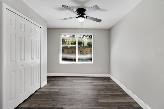 unfurnished bedroom with a ceiling fan, a closet, baseboards, and dark wood-type flooring