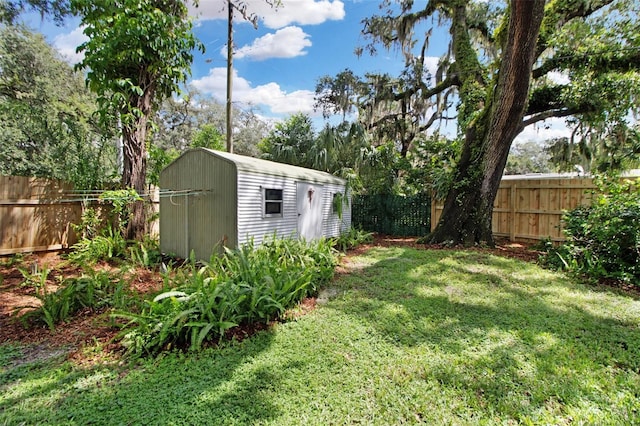 view of yard with a storage shed, a fenced backyard, and an outbuilding