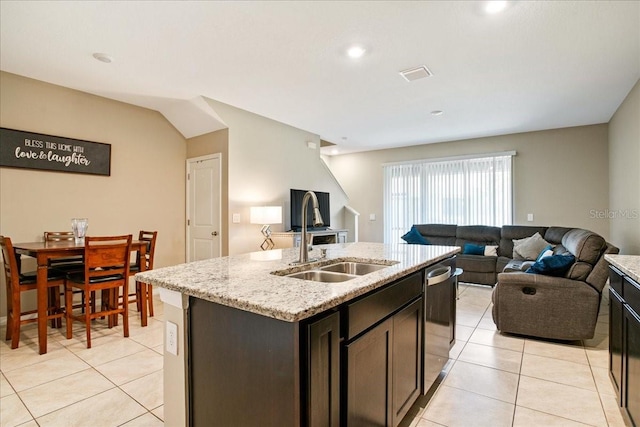 kitchen with open floor plan, stainless steel dishwasher, light tile patterned floors, and a sink