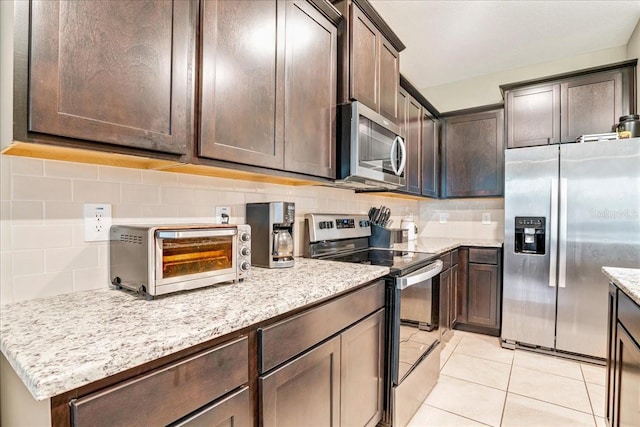 kitchen featuring dark brown cabinets, appliances with stainless steel finishes, decorative backsplash, and a toaster