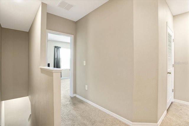 hallway featuring carpet, baseboards, visible vents, and an upstairs landing