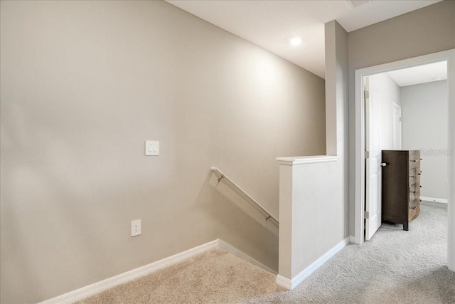 corridor featuring carpet floors, baseboards, and an upstairs landing