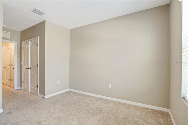 unfurnished room with light carpet, visible vents, and baseboards