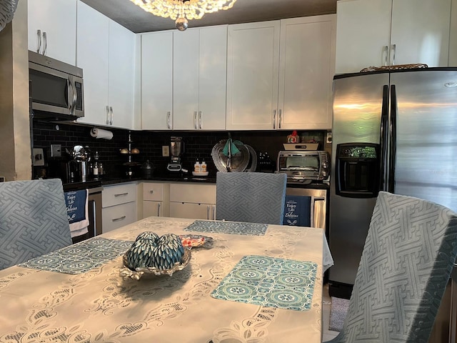 kitchen with appliances with stainless steel finishes, white cabinetry, and tasteful backsplash