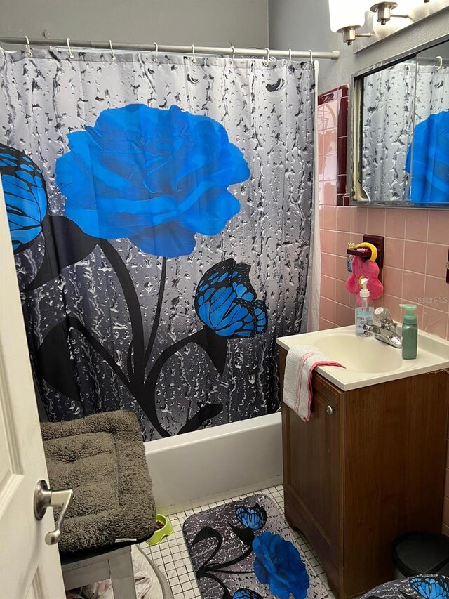 bathroom with vanity, shower / bathtub combination with curtain, tile patterned floors, and tasteful backsplash