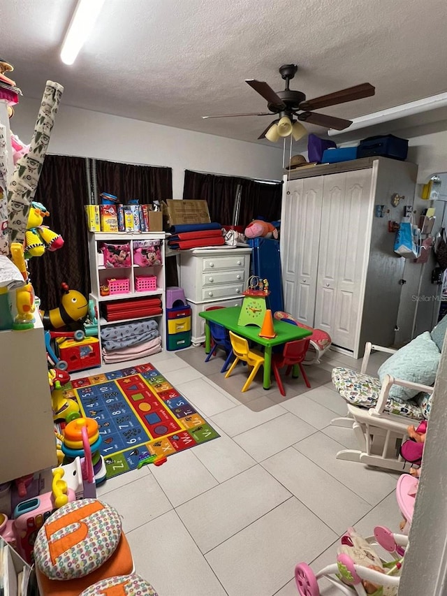 game room featuring a textured ceiling, light tile patterned floors, and ceiling fan