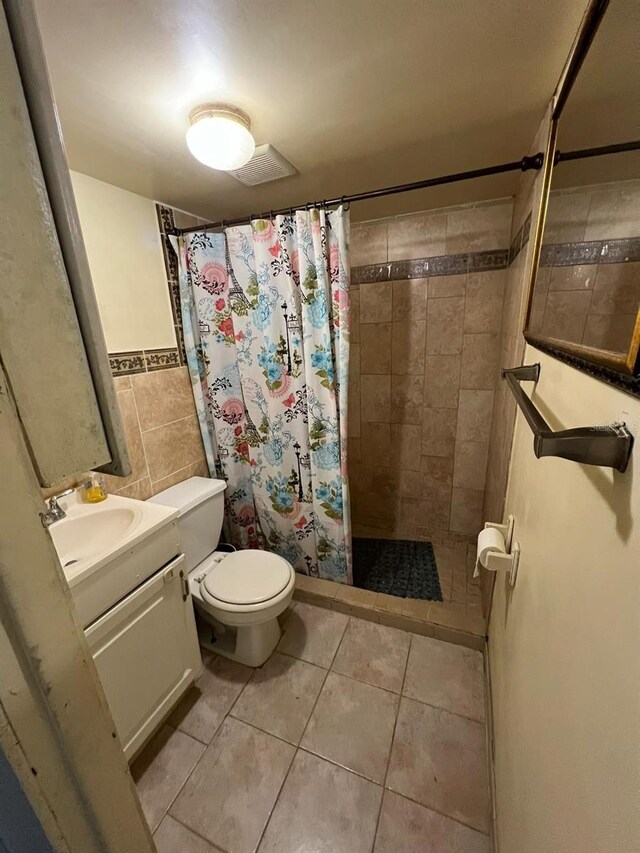 bathroom featuring toilet, tile patterned flooring, vanity, tile walls, and a shower with shower curtain