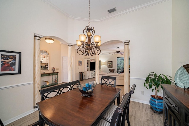 dining room with ceiling fan with notable chandelier, crown molding, decorative columns, and light hardwood / wood-style floors