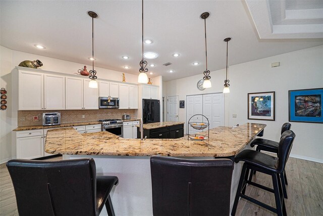 kitchen with stainless steel appliances, decorative backsplash, hanging light fixtures, white cabinets, and a large island