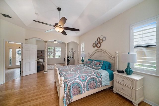 bedroom with decorative columns, vaulted ceiling, light hardwood / wood-style flooring, and ceiling fan